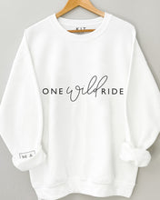 Load image into Gallery viewer, hanging whit jumper with rolled up sleeves featuring one wild ride slogan in black and MAMA logo on sleeve hanging on a wooden coat hanger against a grey background
